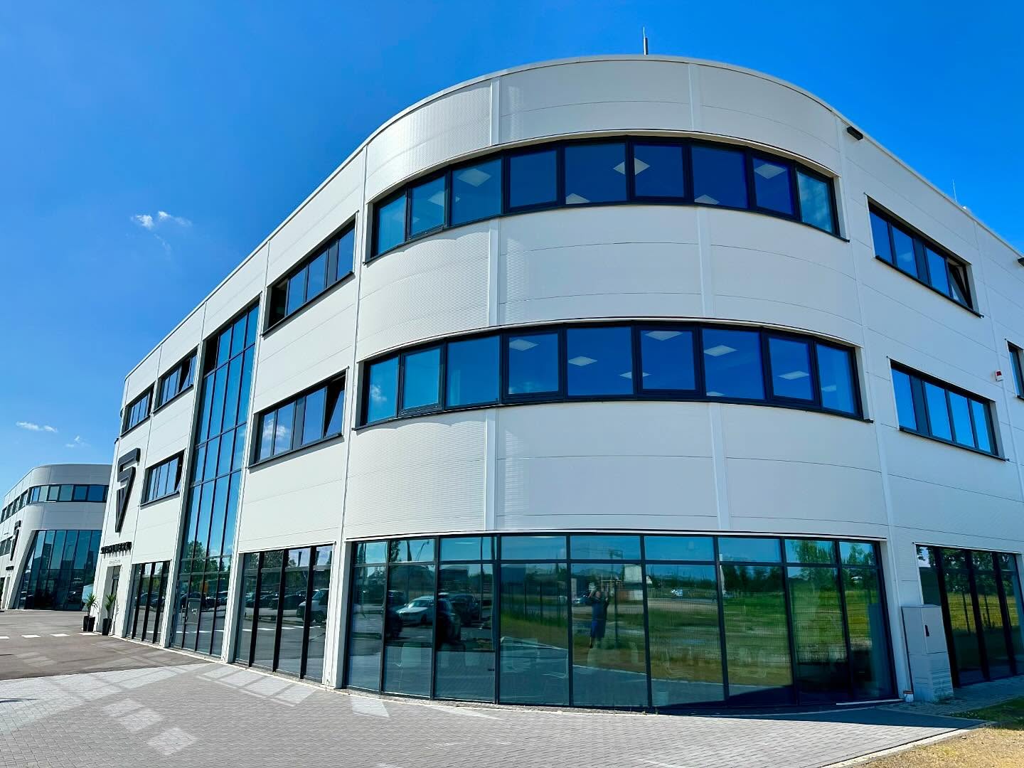 Gerundete Glasfassade eines Service-Centers mit Fensterbändern und gläsernem Eingang.