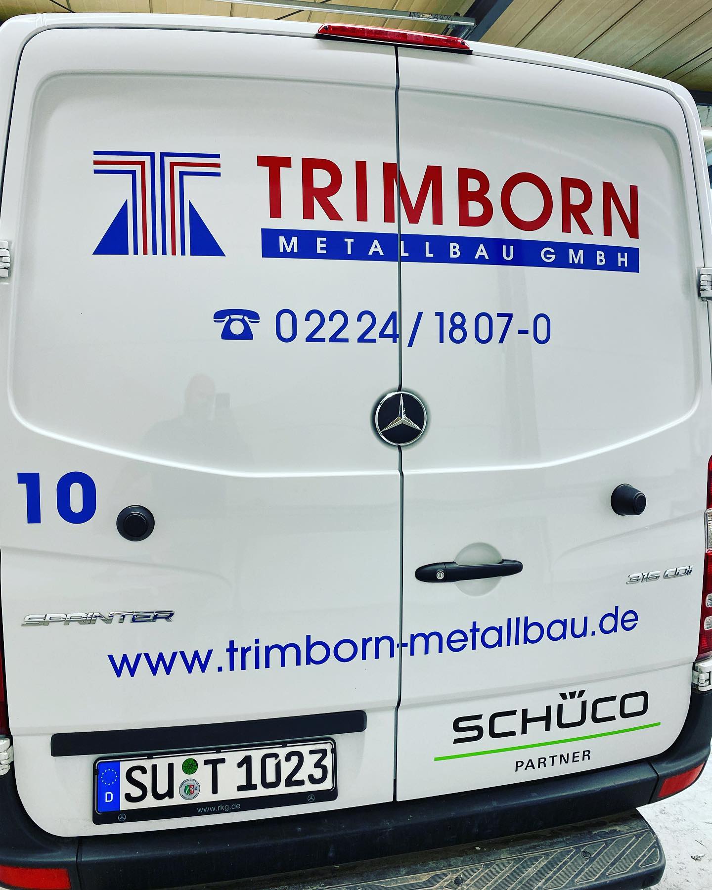 Beschriftete Montage- und Servicetransporter mit Logo nebeneinander.