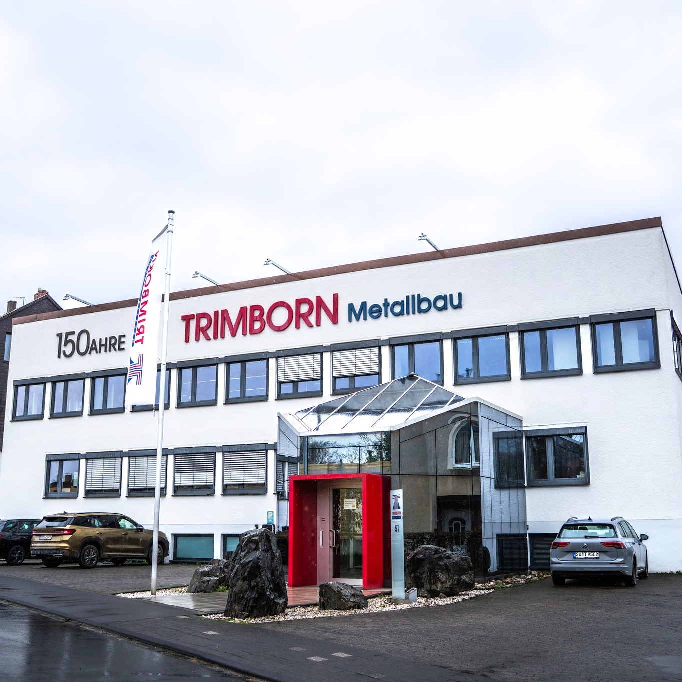 Firmengebäude mit dem Schriftzug TRIMBORN Metallbau und Fahnen.