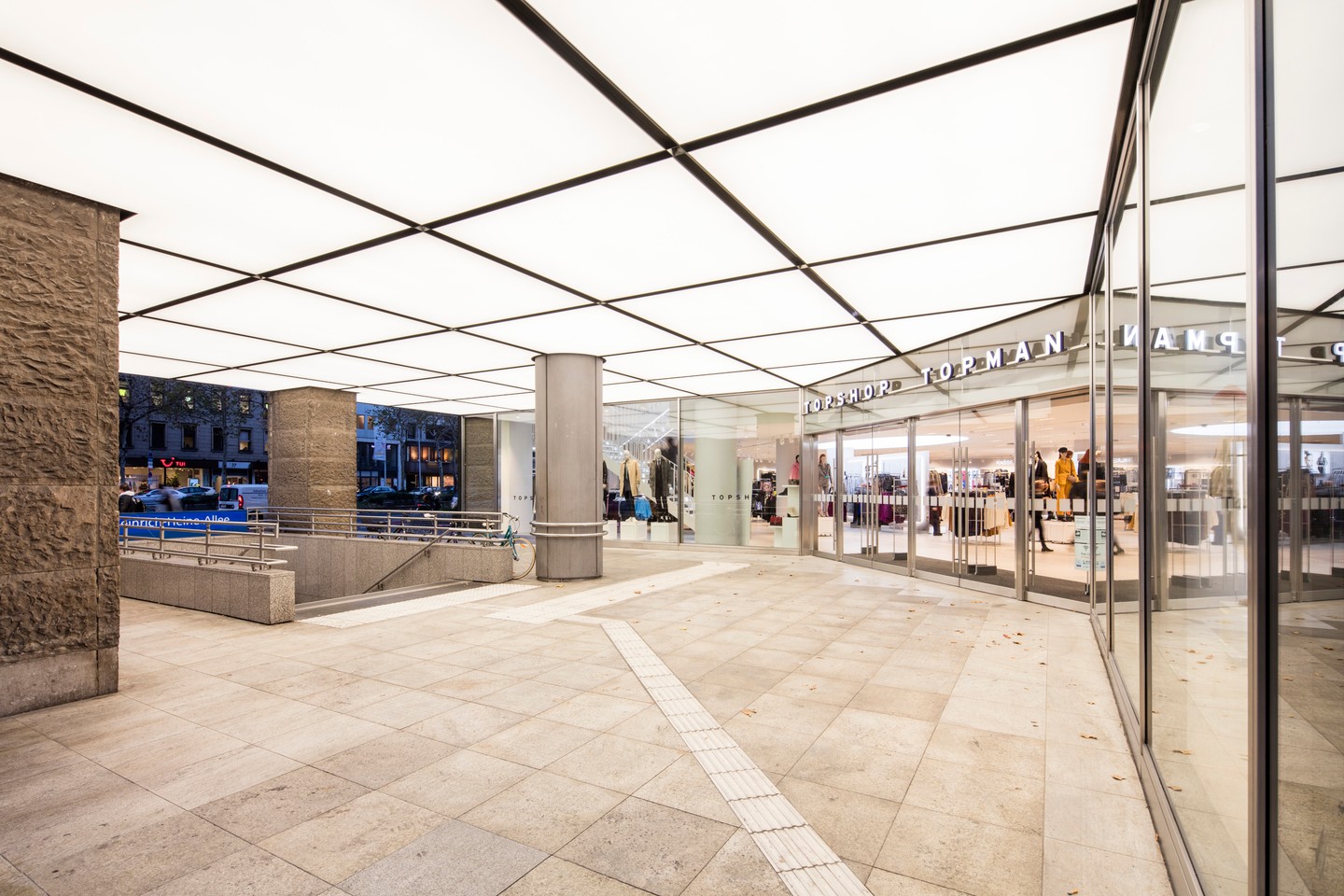 Eingangsportal der GALERIA Kaufhof an der Königsallee in Düsseldorf, mit gläserner Passage und Lichtdecke.